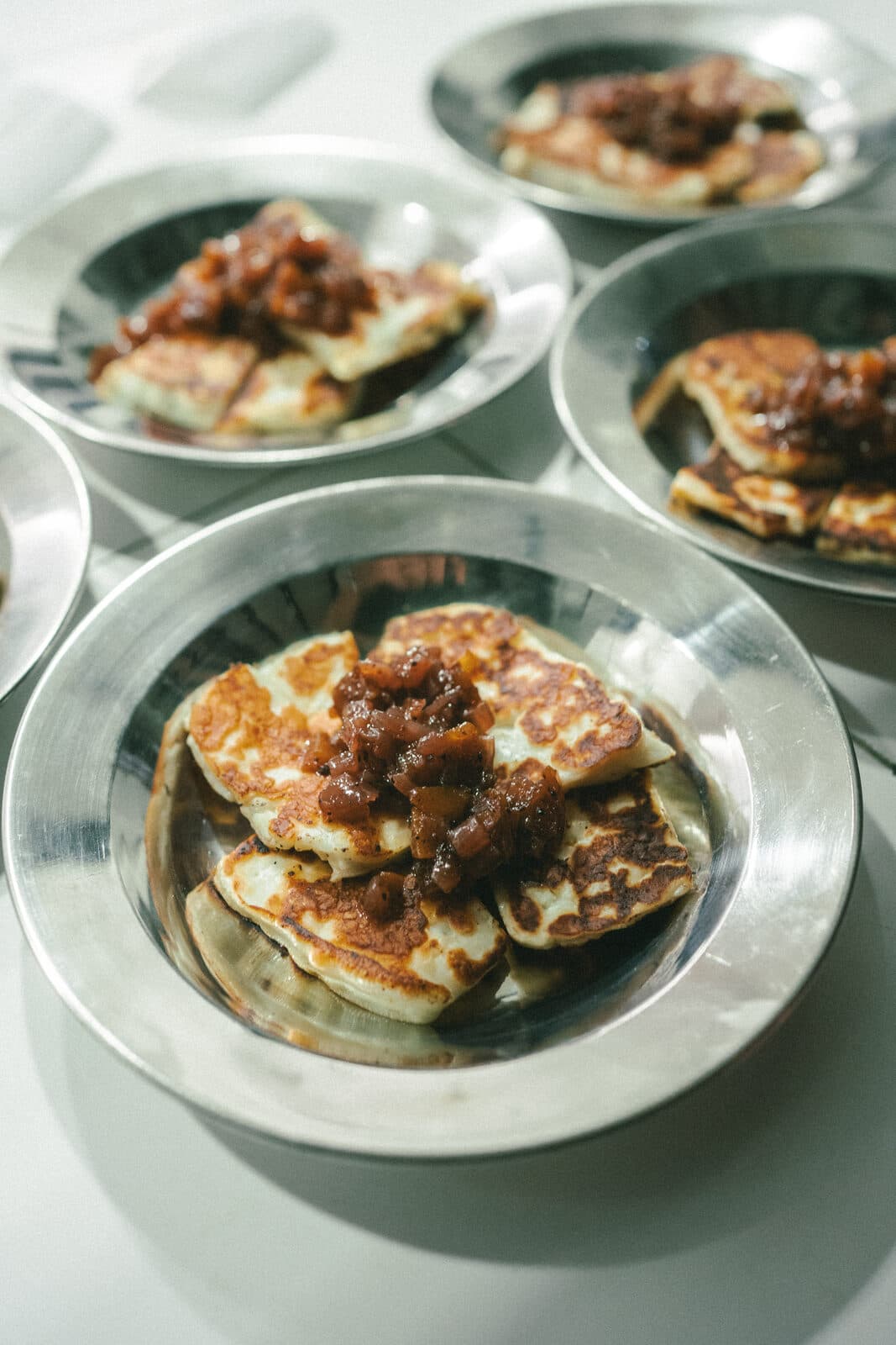Grilled halloumi with a dark relish, served in metal dishes at TEJÁ.