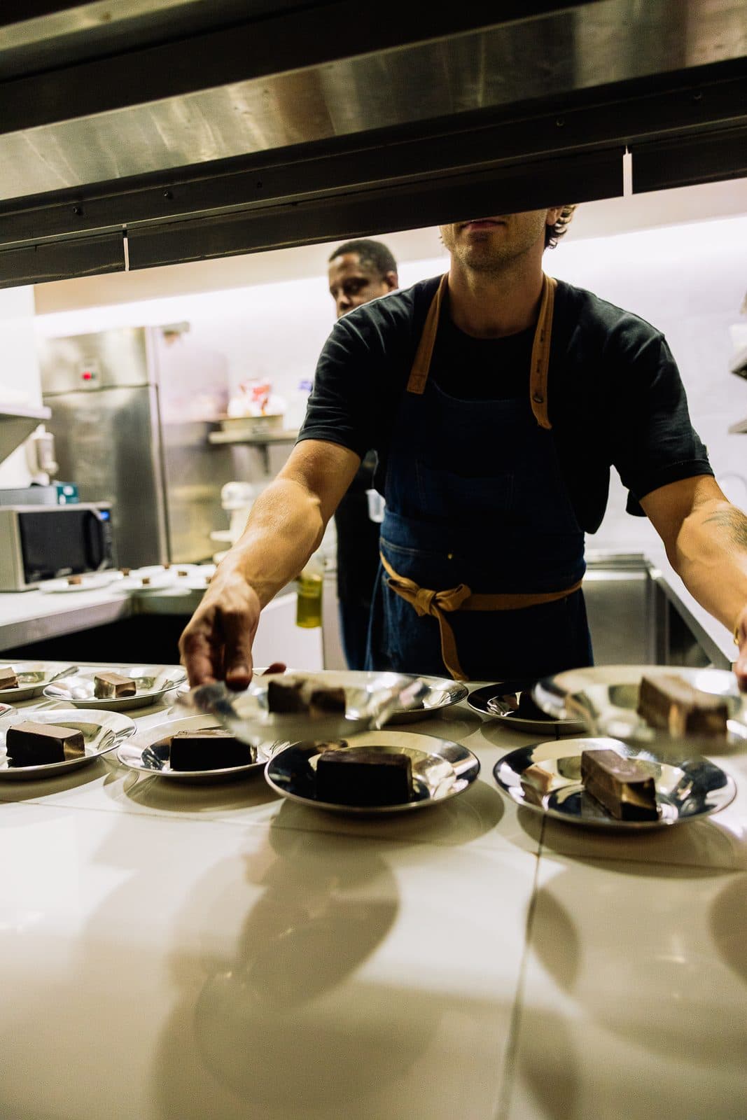 A cook plating dishes at the kitchen pass.
