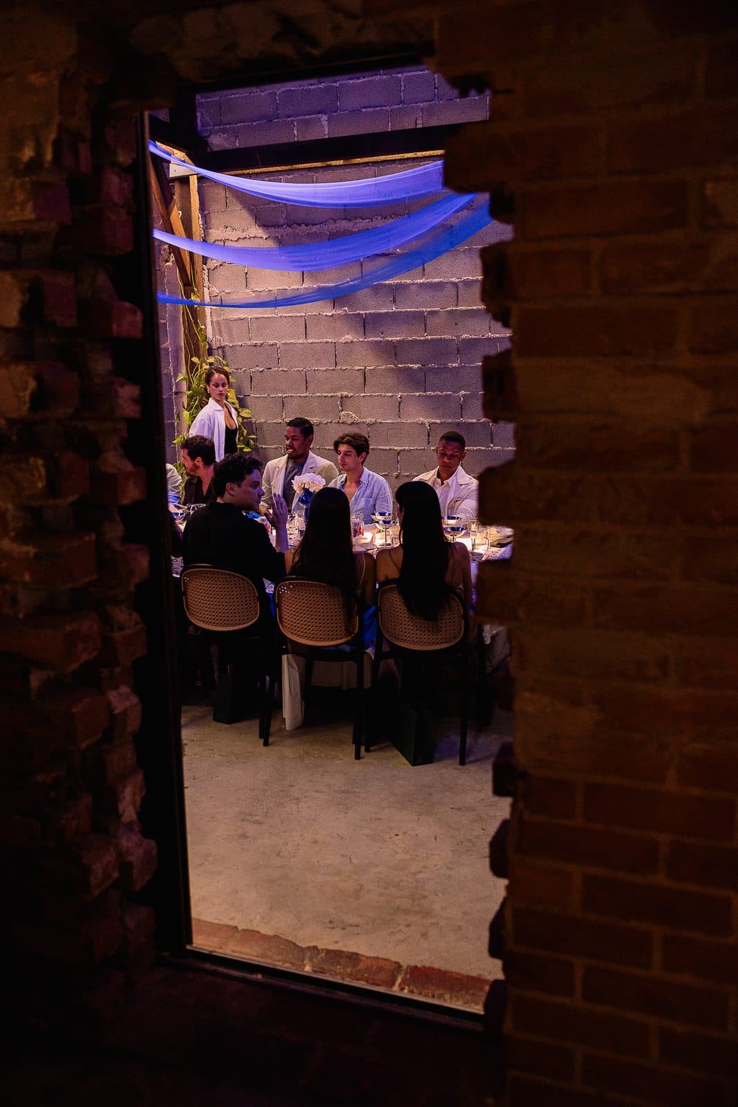 The long table seen through a doorway in the brick wall.
