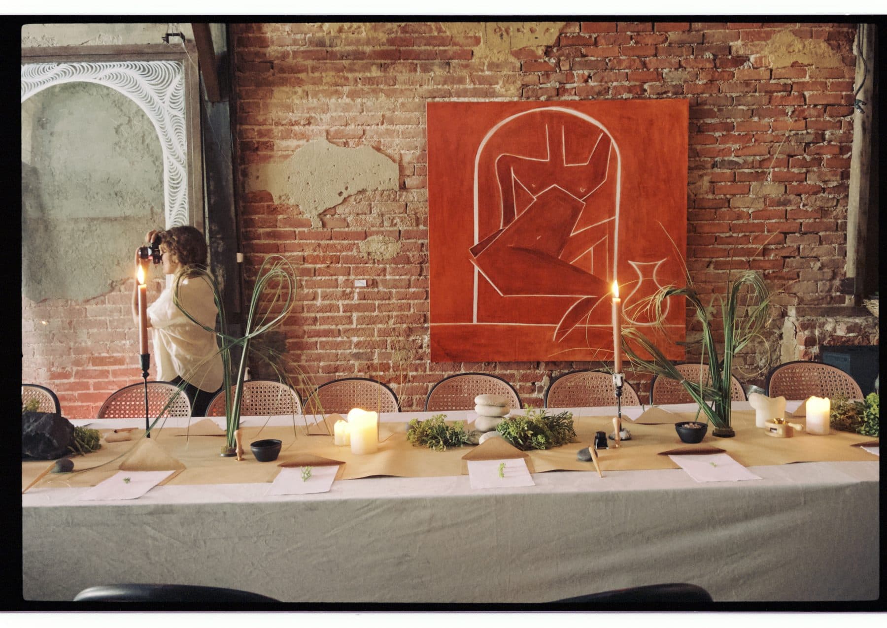 A long table set with paper and candles against the brick wall.