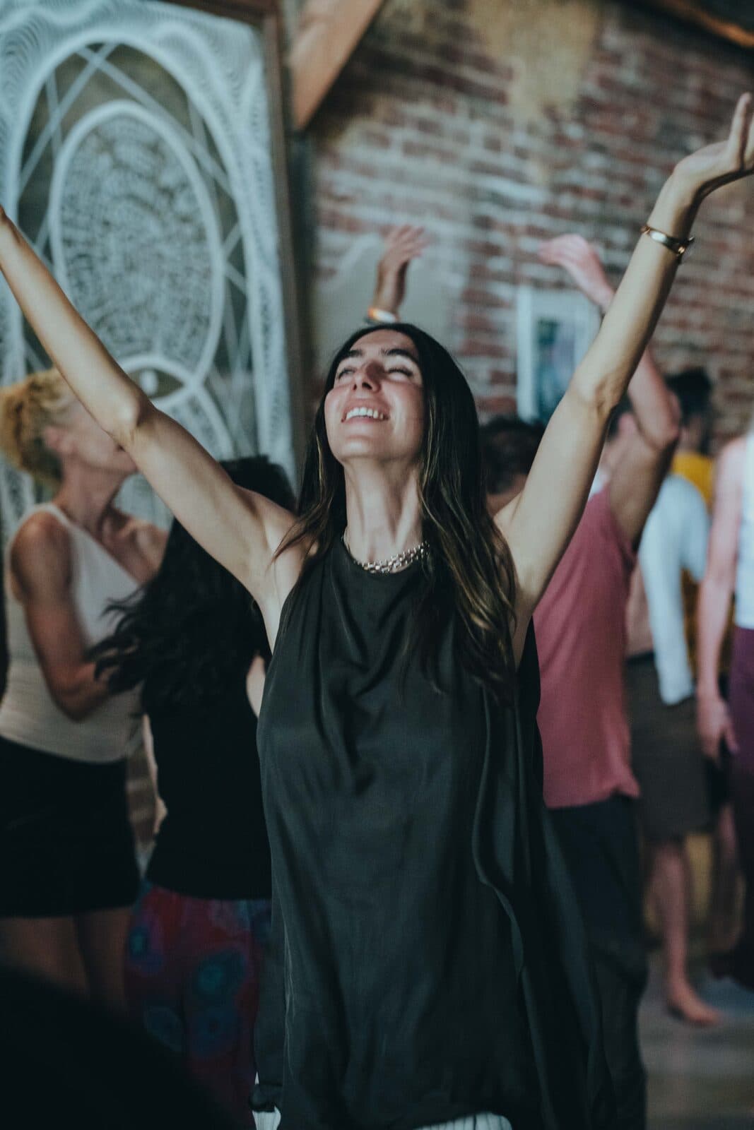 A woman with her arms raised during a movement session in the hall.