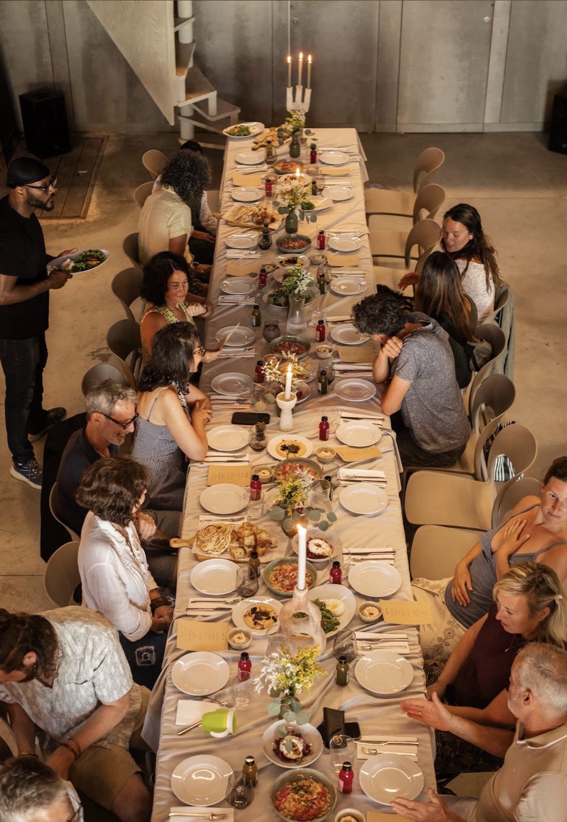 looking down on a full long table at teja, people eating and talking along both sides